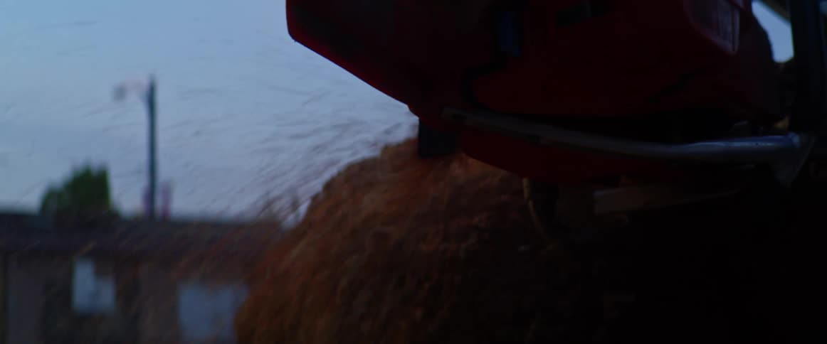 A wood chipper machine blows mulch in front of a row of businesses