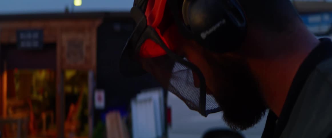 Man in hard hat and ear protection outside business at night