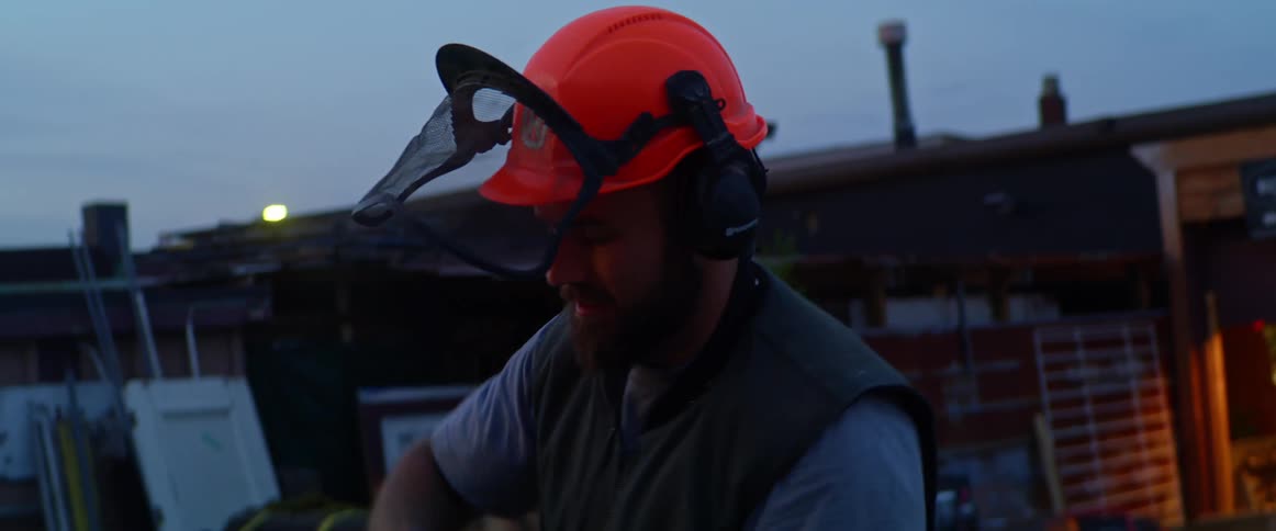 A construction worker pulls the cord on a chainsaw outside