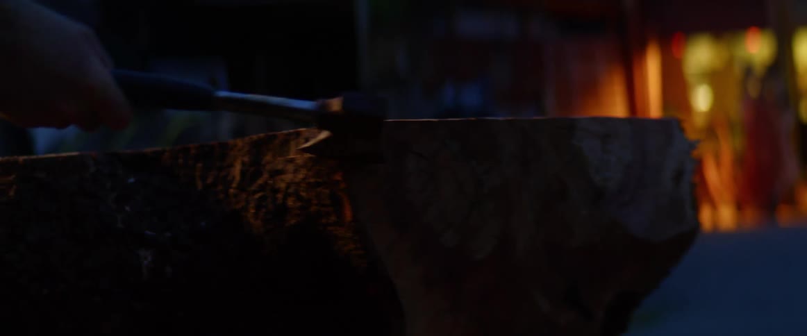A man hits a log with an ax