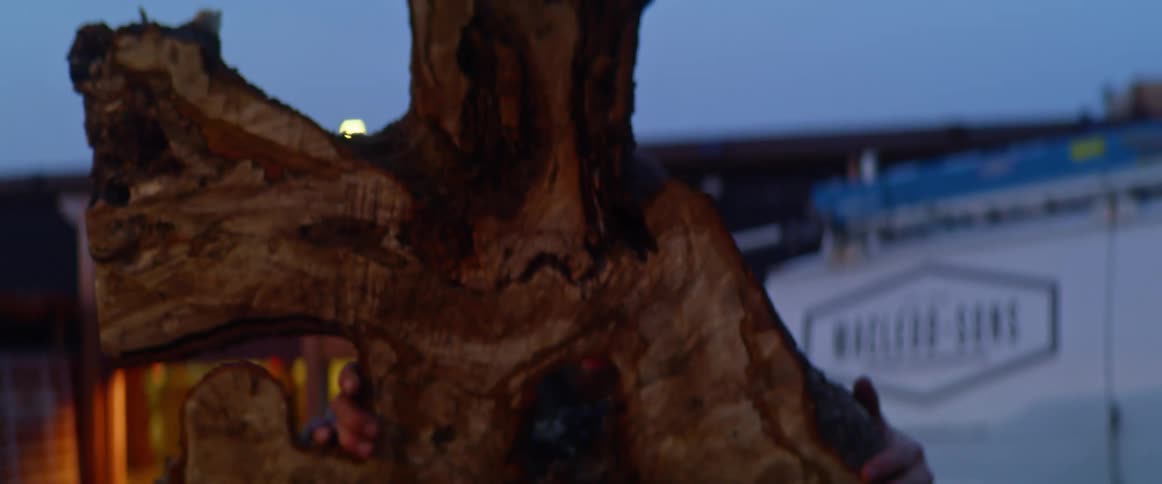 Man lifts large piece of cut raw edge lumber outside business
