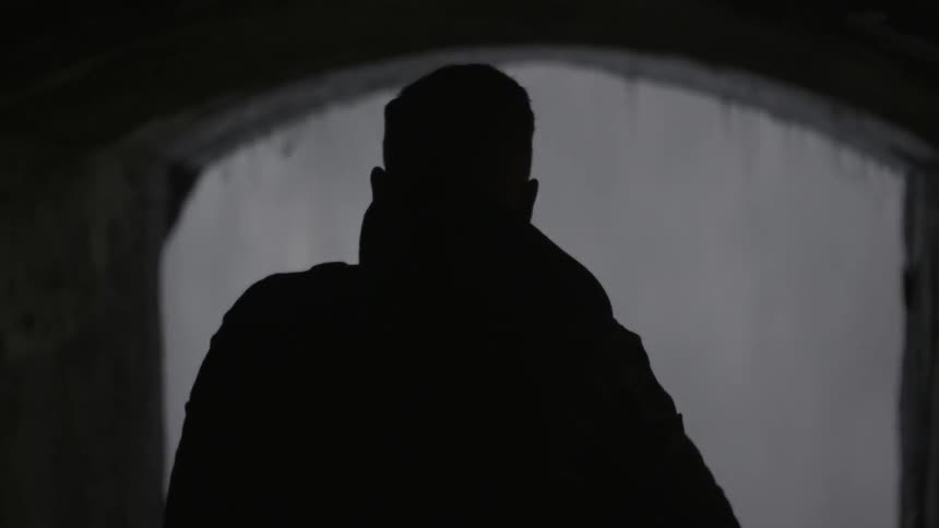 Man looking through an archway at heavy water fall on the other side