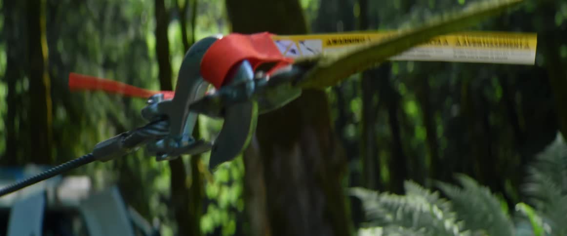 Hinged hook connects strap and cable used to pull in forest near commercial truck