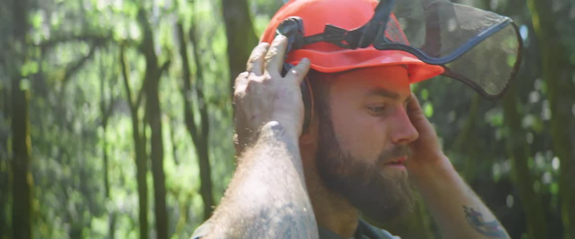 A man putting on a helmet in the forest