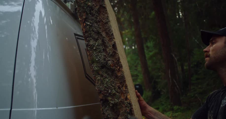 A worker putting a piece of wood on the side of a van