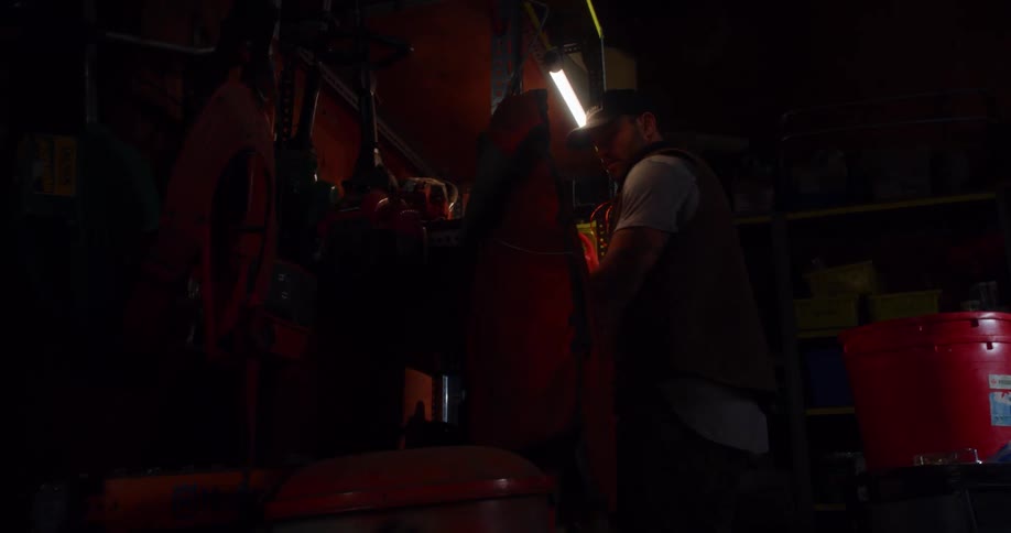 A man picks up a tool in his garage