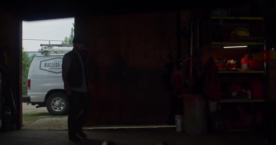Man slides open door to workshop and walks to shelves