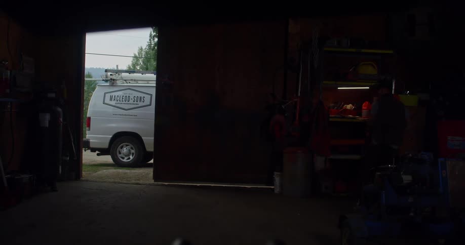 A man enters a building to retrieve a chainsaw before heading back out