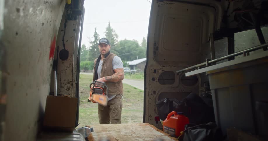 A man places his chainsaw in the van