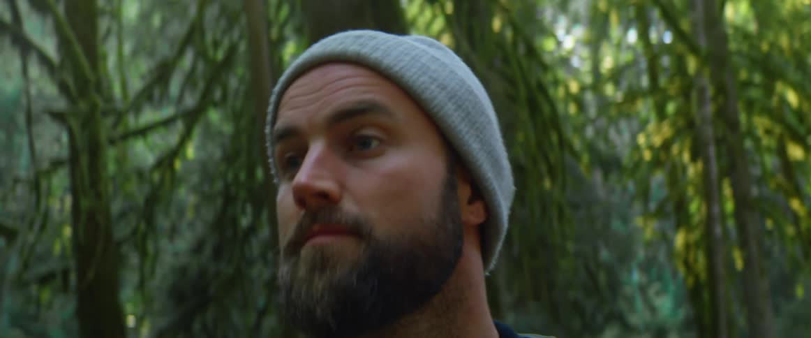 A man is standing outdoors in the forest