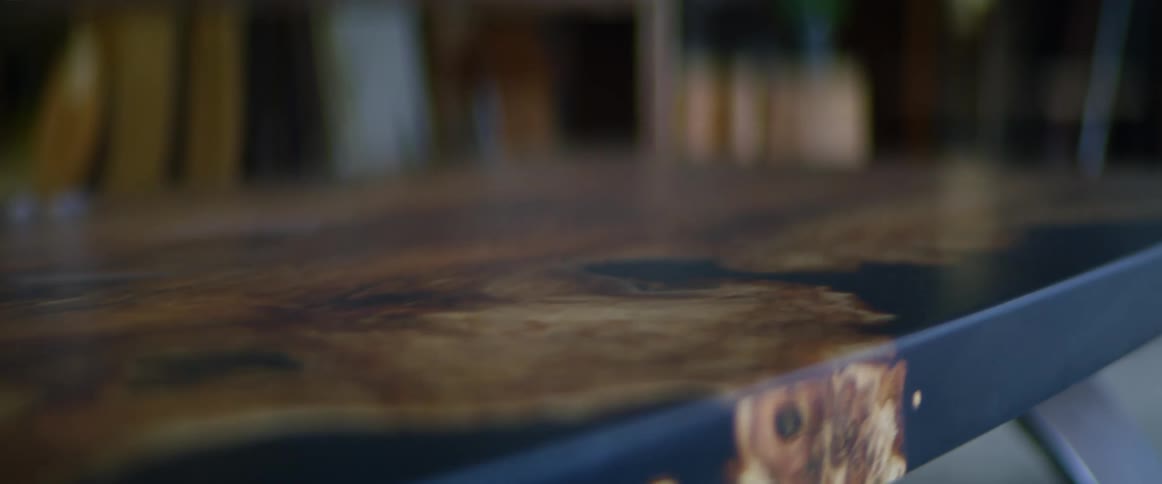 A black table with a wood overlay design sits in a designers work shop