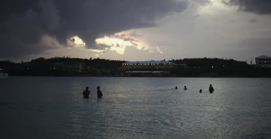 People relax in the ocean outside of a city in the evening
