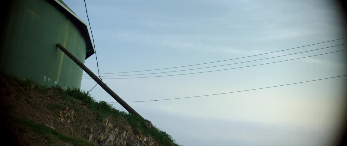 Wooden prop supports building wall near cables under cloudy sky