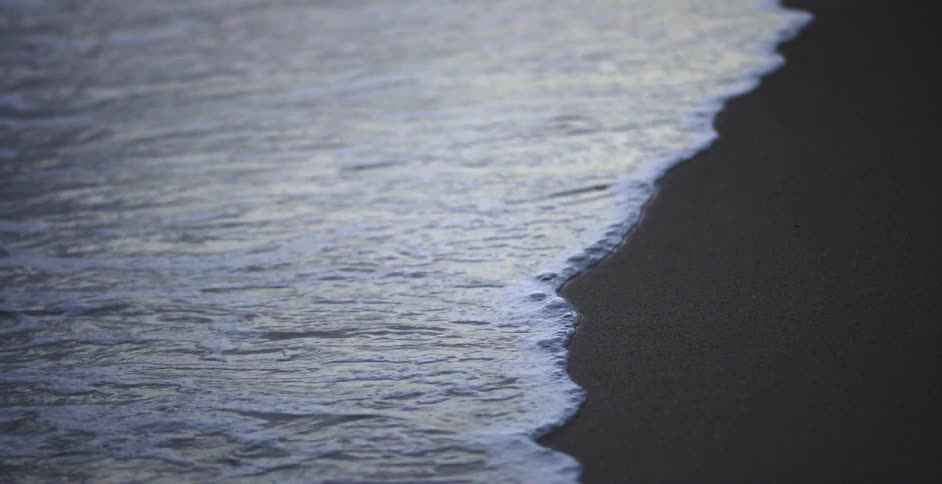 Ocean waves wash into the smooth sand of the shore during the day