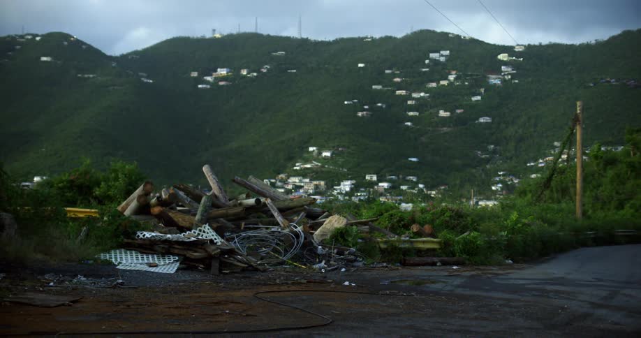Trash heap sits in front of town occupying valley and slope of green mountain