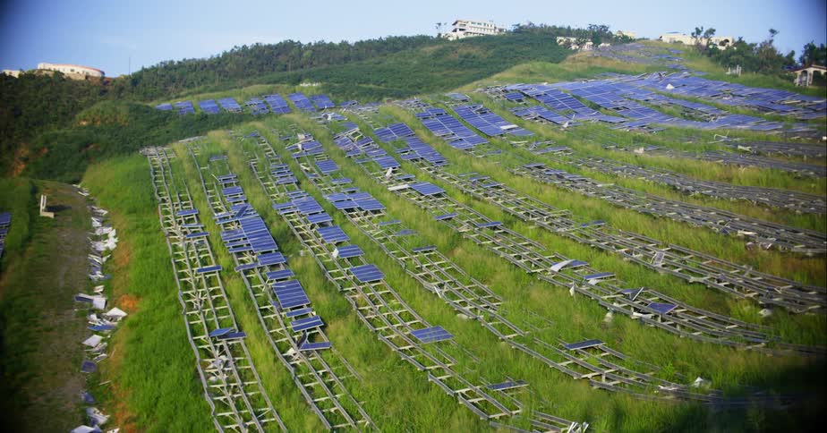 A field of solar panels on a hillside on a sunny day