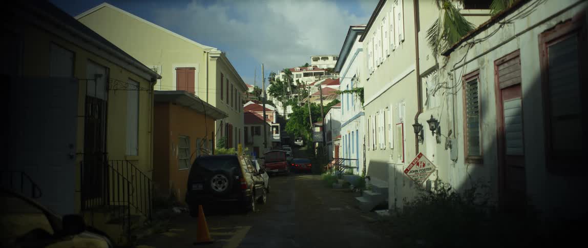 Cars on a narrow street in a neighborhood