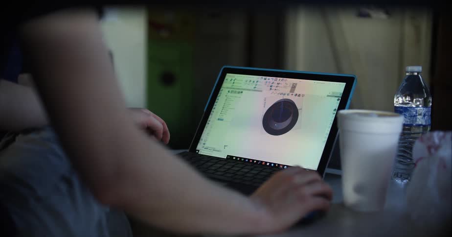 Woman with a black t shirt sits and uses a laptop in a room