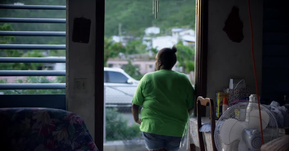 Woman reclining pensively on the doorway of her humble home