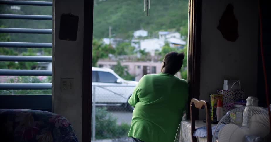 A woman looks out the doorway of her home