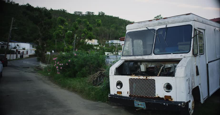 An old abandoned van left in the vegetation beside a small road in the hills