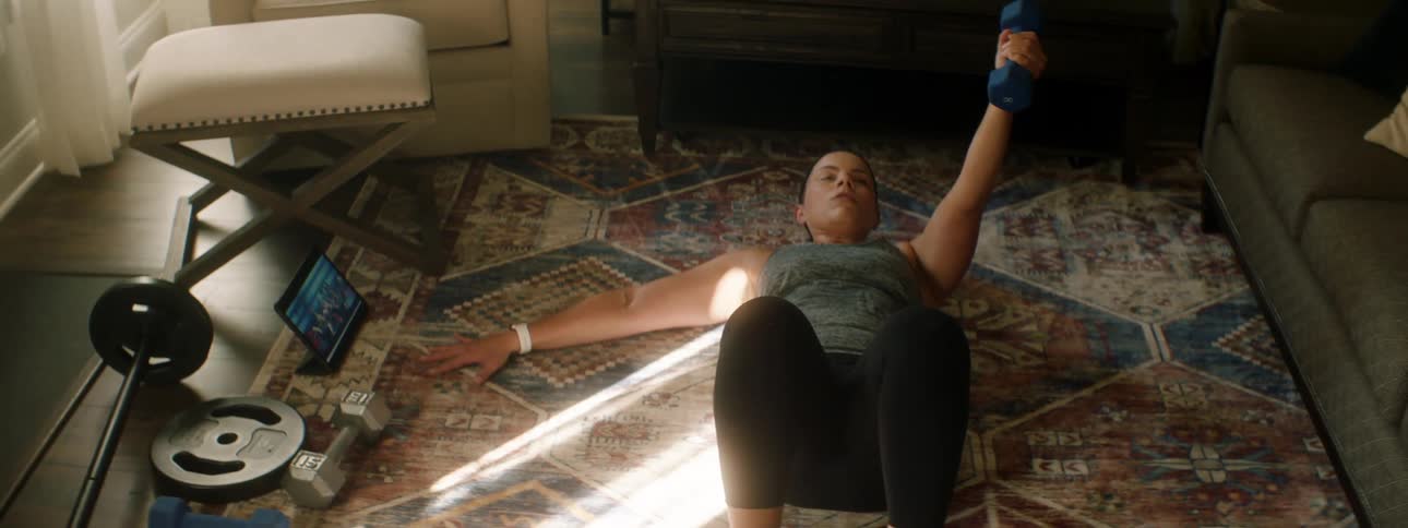 A woman is lifting weights in her house