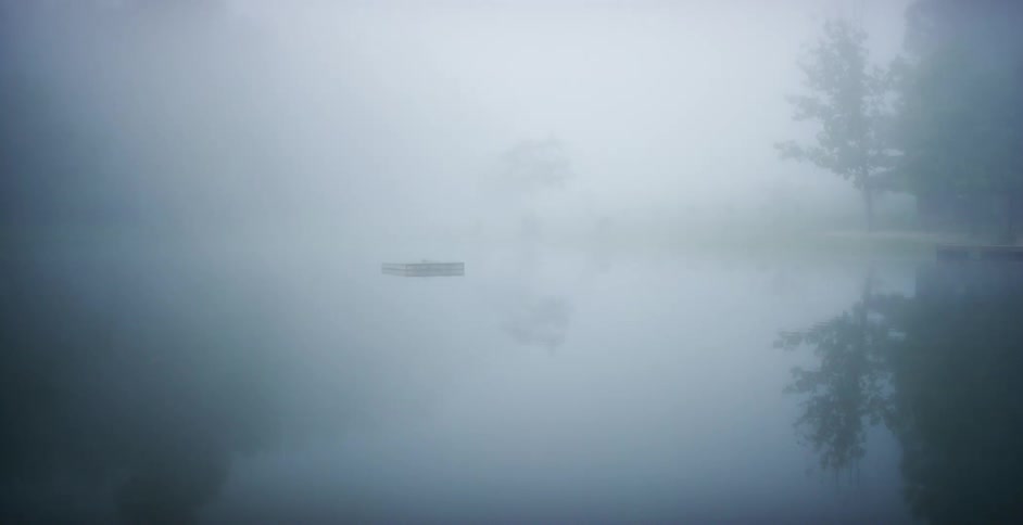 A boat floating on a lake on an extremely foggy day
