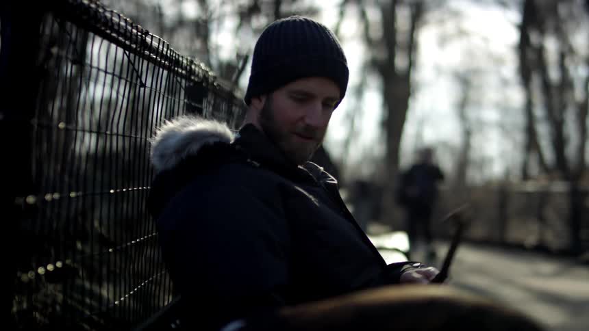 A man and his dog sitting down on a bench in a park