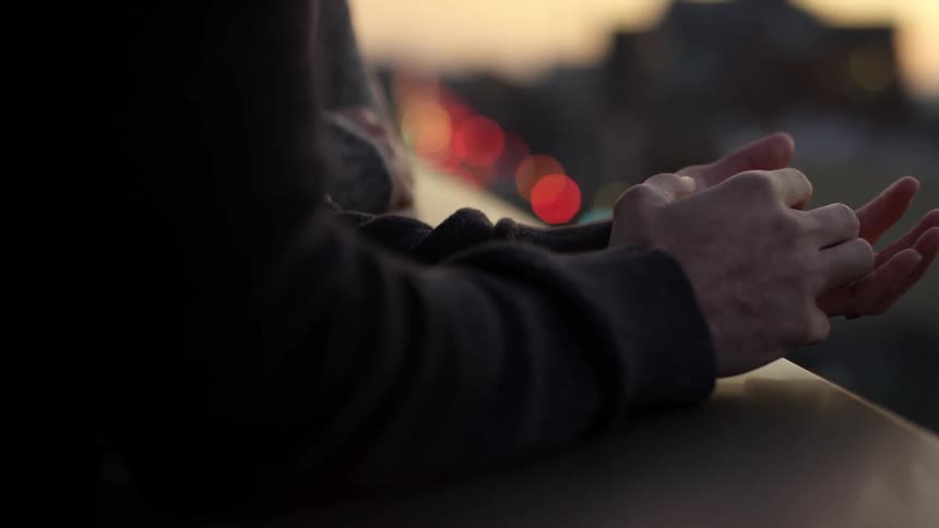 A woman rubs a mans arm as they sit together outside