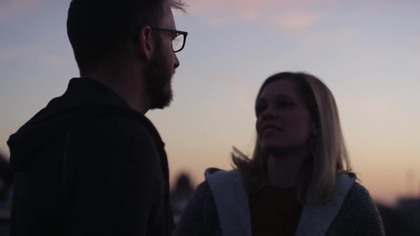 A man and woman standing outside talking and laughing