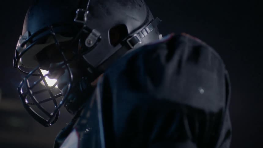 A person in football gear stands in a brightly lit stadium