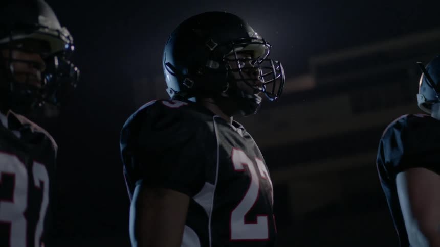 Football players are jumping up and down at night