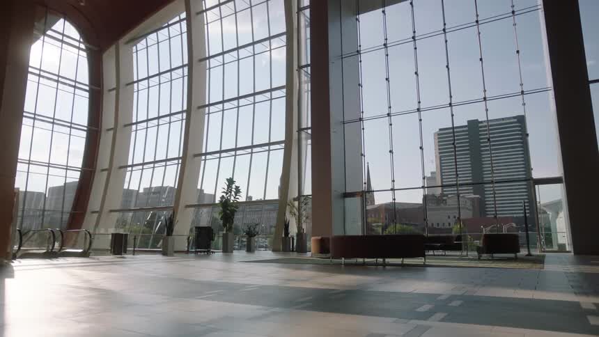 A large room has walls made of all windows on a sunny day