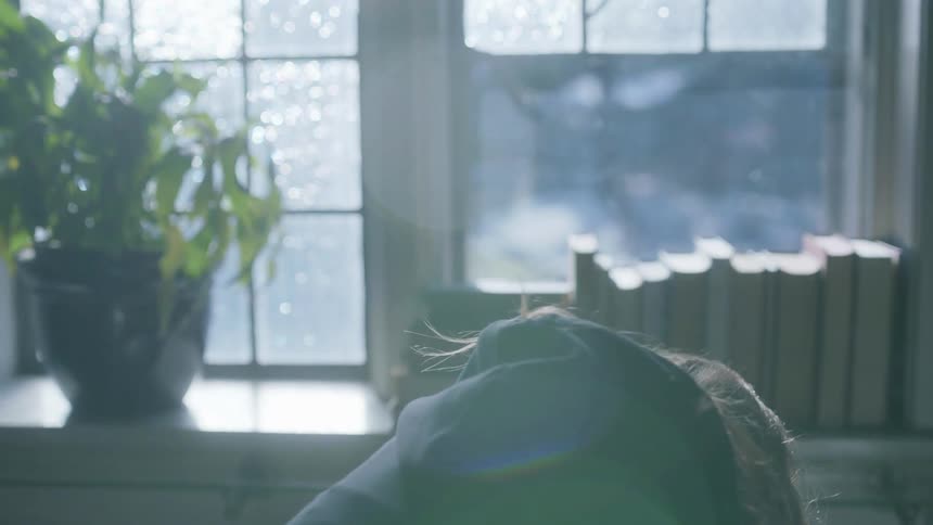 A teenage girl at homes bends over and hangs her head
