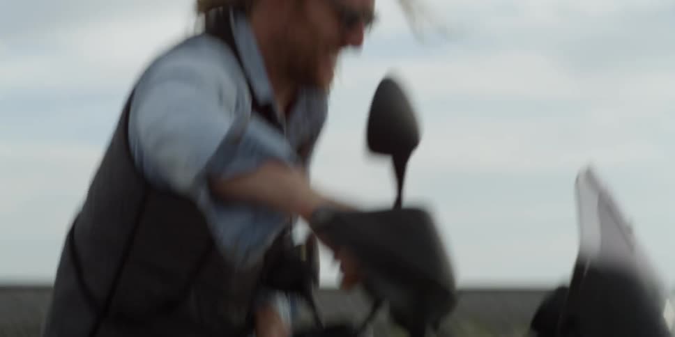 A man pushes his motorcycle outdoors