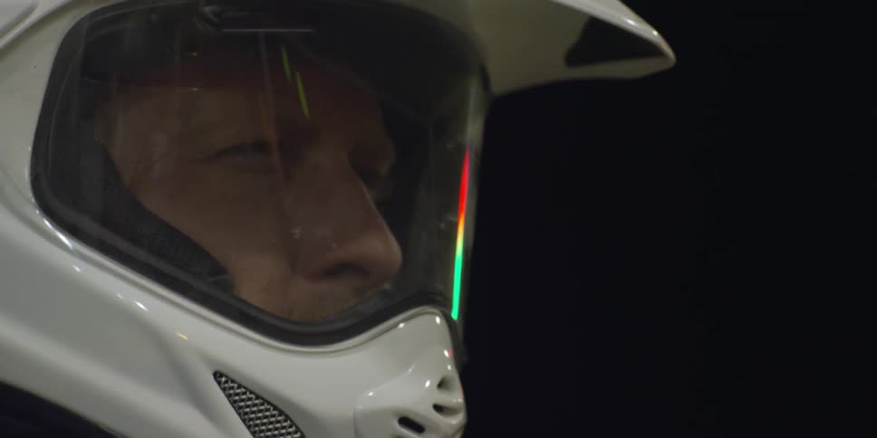 A man blinks as lights reflect off his helmet visor