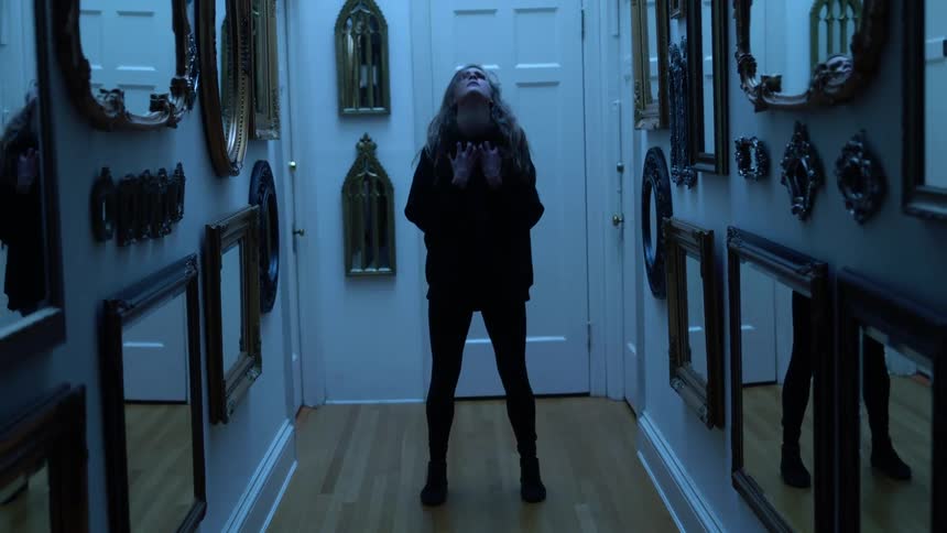 Woman dances in wooden floored hallway full of hanging mirrors
