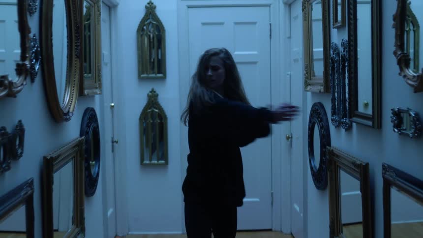Young woman dances in hallway with many mirrors on walls