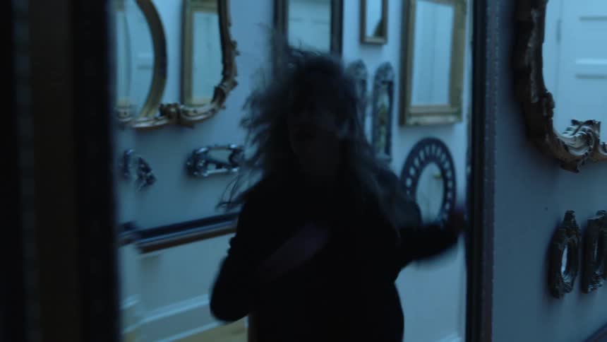 A woman dancing in a hallway full of mirrors