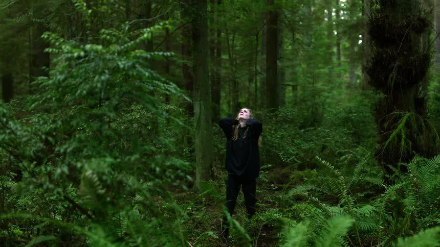 A woman is walking through a forest during the day
