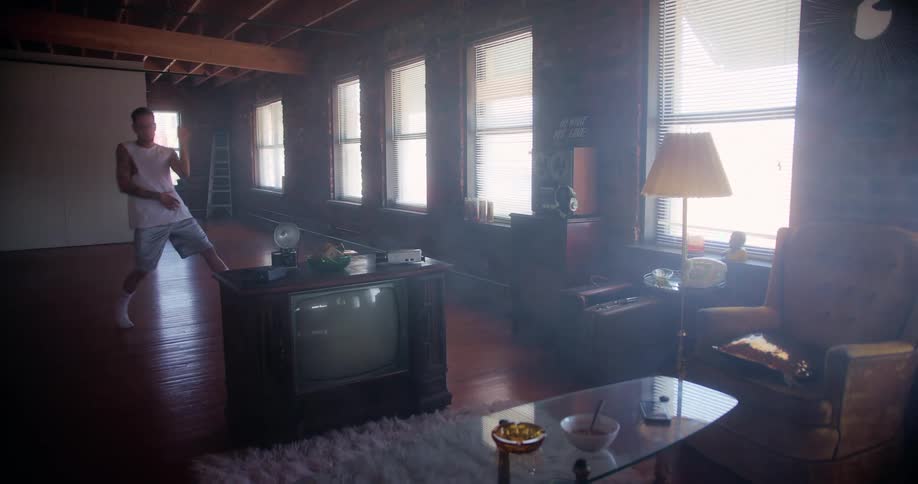 A man dances in the living room of a house as sunlight shines in through the windows