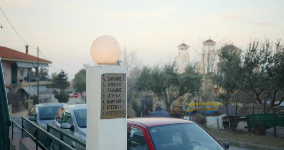 A man walks down the street past a row of vehicles parked near businesses in a city