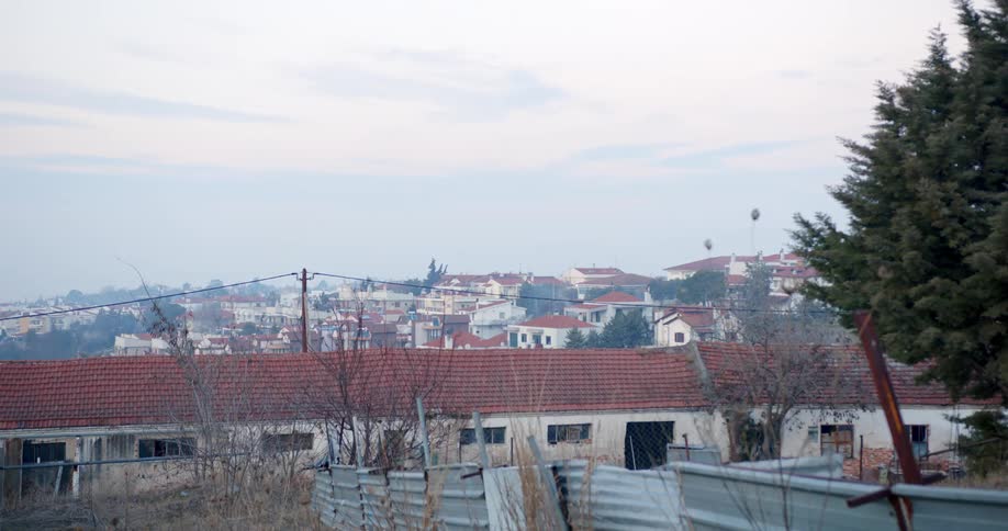 Red roofed buildings bounded by metal fence panels stretch to horizon in town