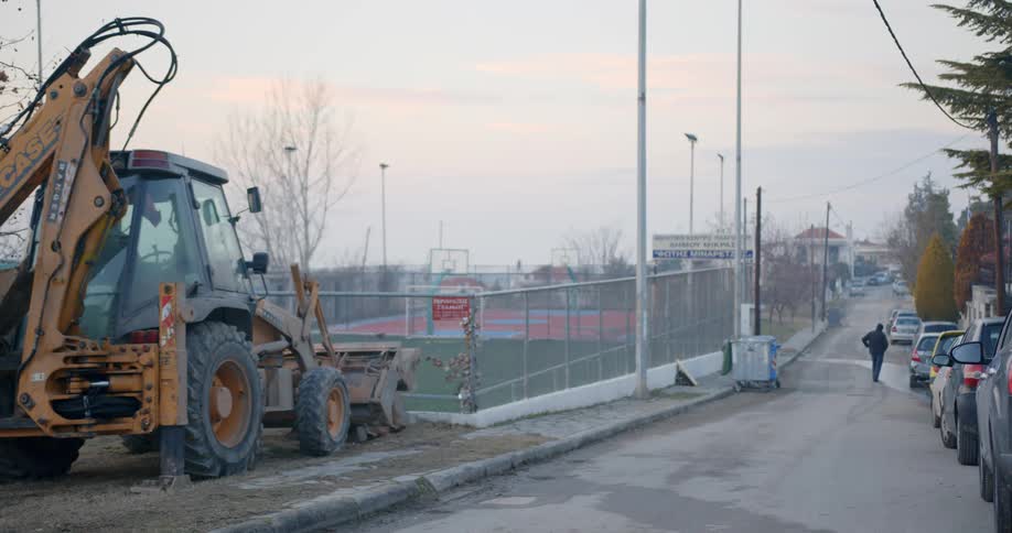 A man walks down a neighborhood street across from a park