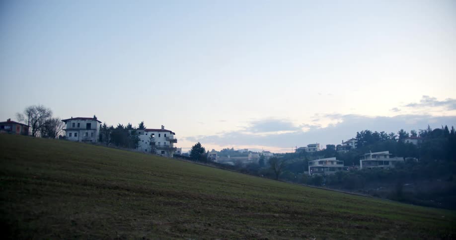 Apartment buildings and homes sit on hills at edge of town and woods