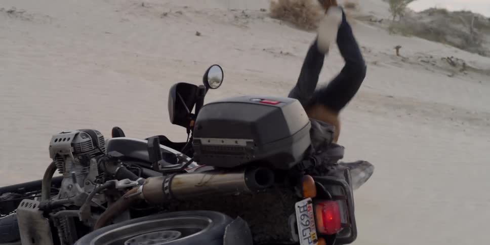 A motorcycle crashes and a man tumbles off of it