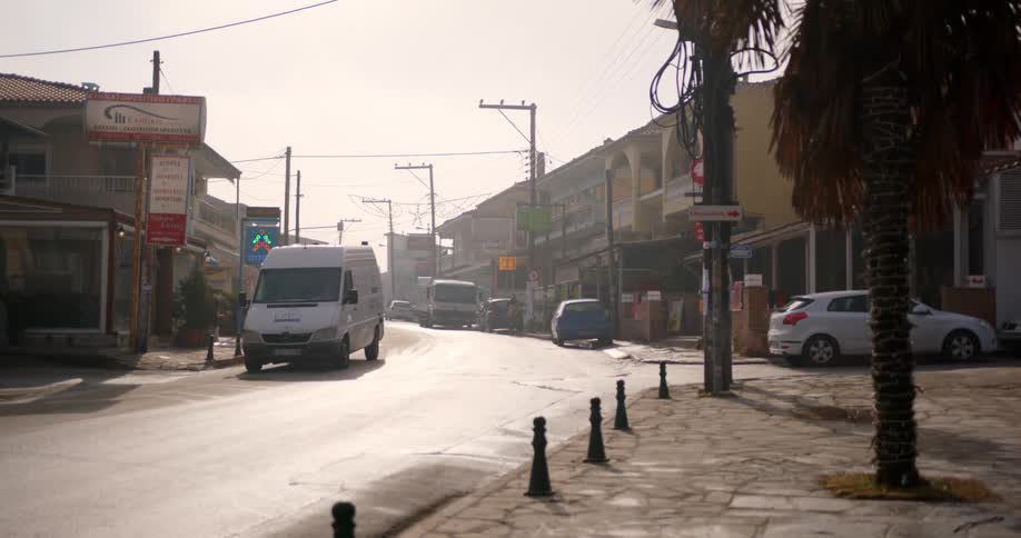 A city street with vehicles and trees with the sky in the background