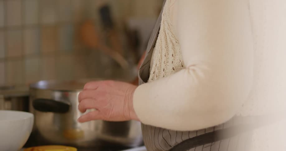Woman wearing an apron stirs the pot of food