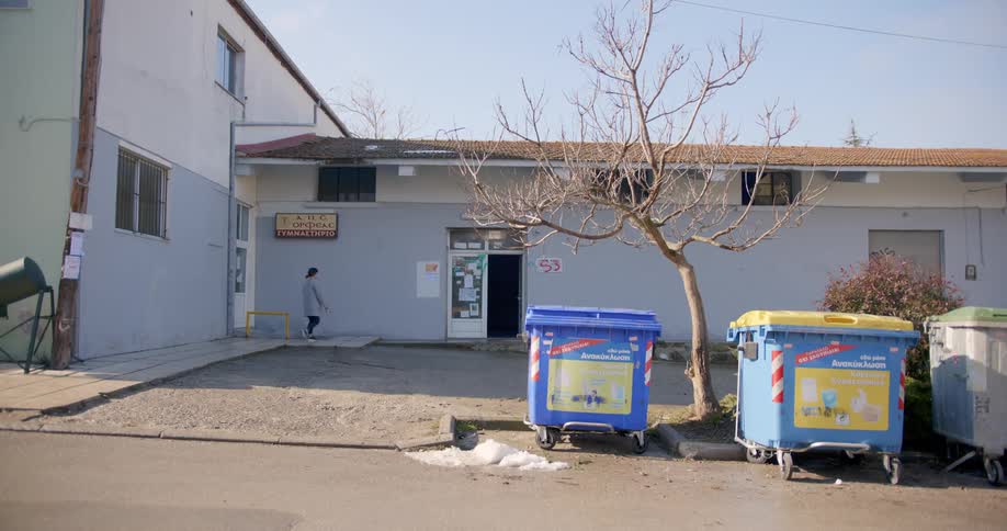 A woman walks down an alley and into the back door of a business