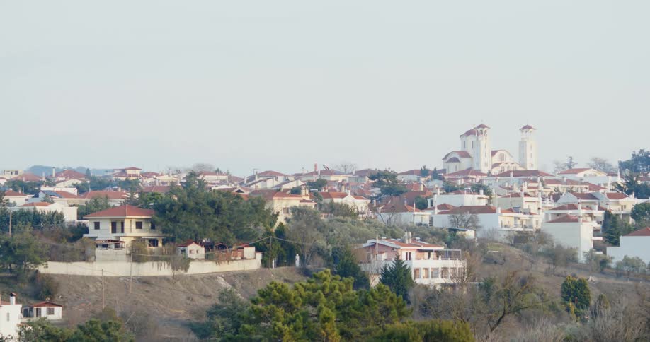 White homes with rust colored roofs are nestled along the shore of a lake